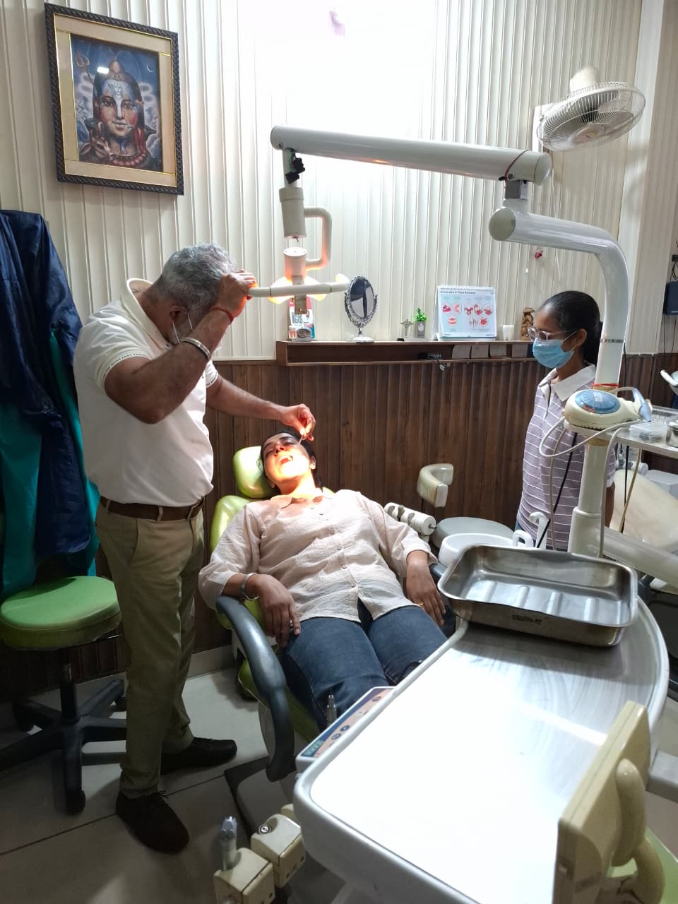 Dentist examining a patient with a dental assistant